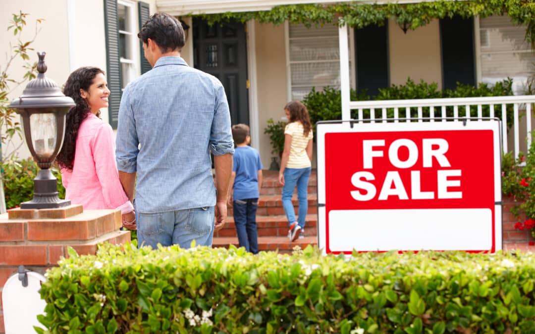 family outside home with for sale sign